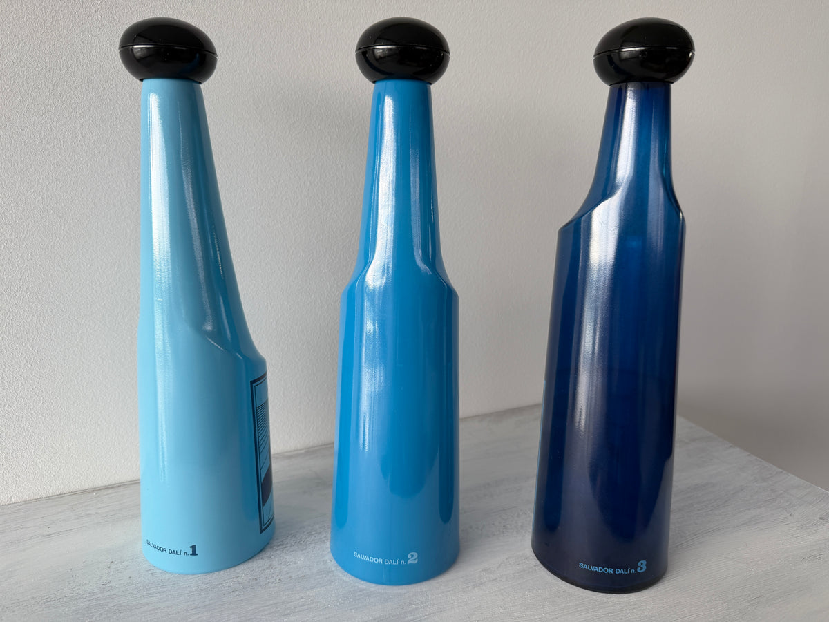 Bottiglie Rosso Antico illustrate da Salvador Dalí con tappi neri e tonalità blu